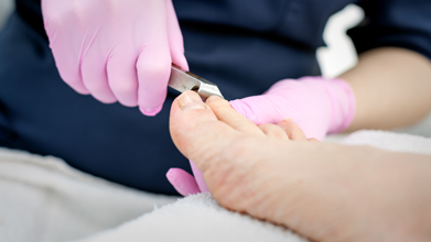 podiatrist clipping clients toenails wearing pink latex gloves
